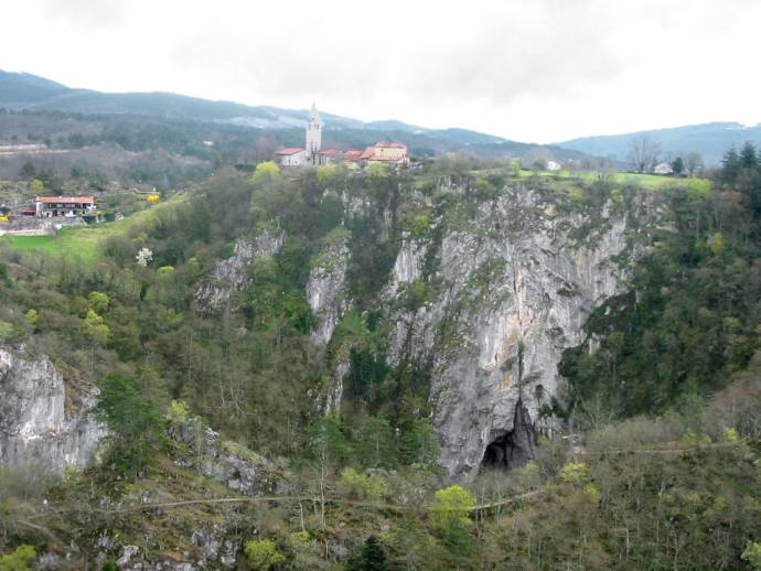 Village Skocjan, Divača, Slovenia. River Reka; resurges twice from under the Karst rock formations. In front below: View into first of 2 huge collapsed parts of cave Skocjanske jame (Mala Dolina).