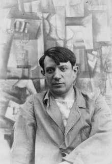 Portrait photograph of Pablo Picasso, in front of his painting The Aficionado (Kunstmuseum Basel) at Villa les Clochettes, Sorgues, France, summer 1912